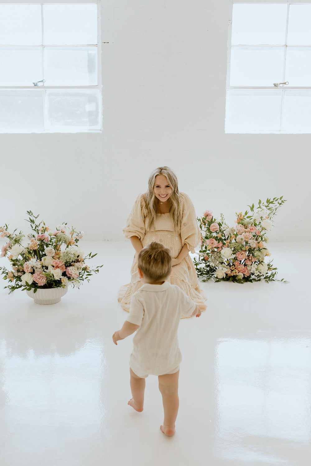 Woman and child in a white room with floral arrangements